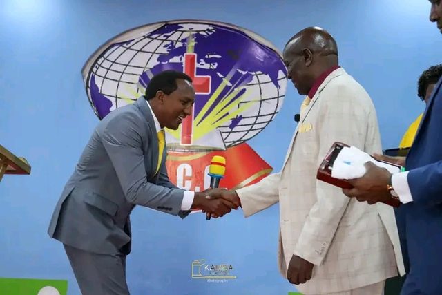 Two bishops shaking hands in front of a church logo