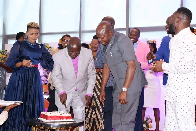 Two bishops cutting a cake as guests look on