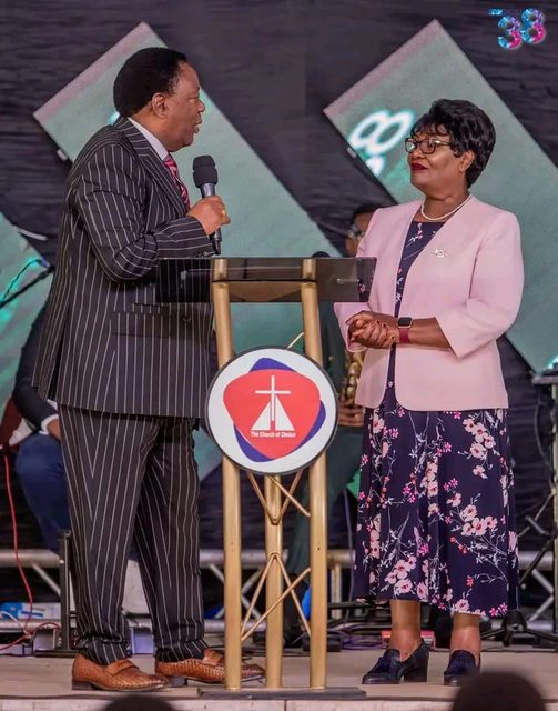 A bishop in a pinstripe suit speaking to a woman at a pulpit